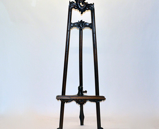 Lot 104: Tall carved easel with adjustable base.