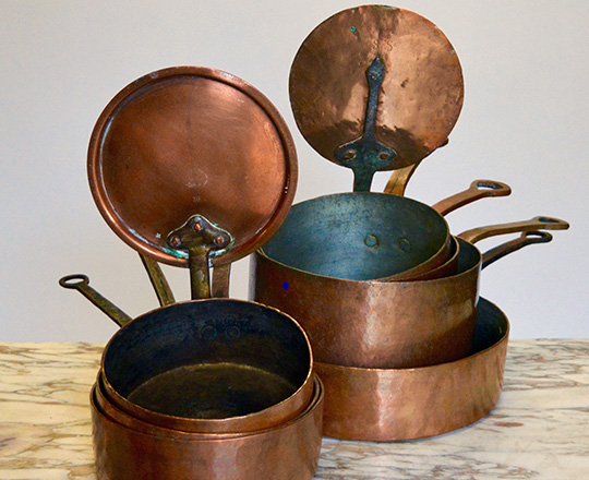 Lot 112: set of seven graduated copper pans with two lids. Max dia.30cm.