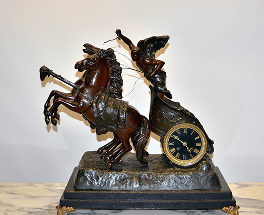 Lot 114: Fairly large bronze wash spelter mantle clock; young gladiator racing with horses on a chariot. H53xW53xD30cm.