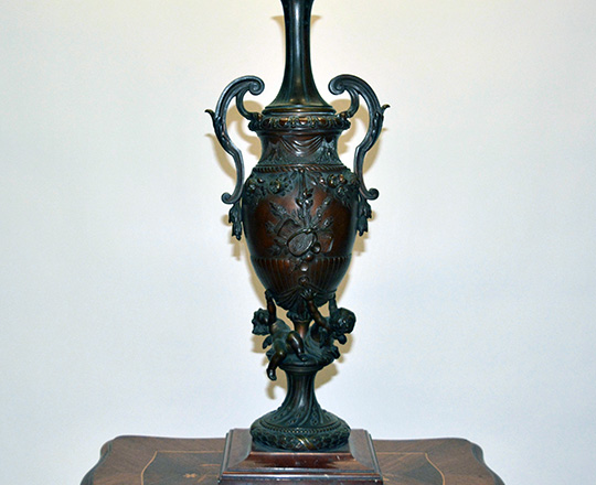 Lot 492: Large 19th cent bronze table lamp with two puttis supporting vase with arts attributes decor. H 62cm.