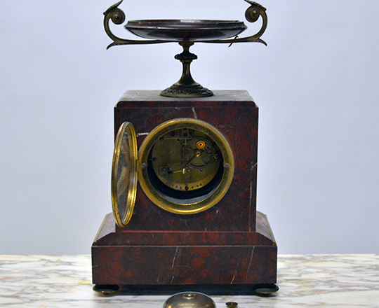 Lot 584_1: 19th c Nap.lll red marble mantle clock topped with a dish and a pair of cassolettes with repair on dishes.